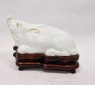Chinese Export style white glazed porcelain model of a boar on wooden stand, kneeling, in the
