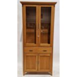 Morris Furniture light oak display cabinet, the top section having two glazed doors opening to