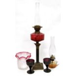 Victorian brass and cranberry glass oil lamp having panelled glass oil well, on corinthian column