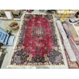 North East Persian signed red ground Meshed carpet with large centralised floral medallion