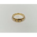 Gold-coloured metal and diamond ring set three old cut diamonds in gold band with scroll shoulders