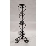 20th century black painted floor standing candle stand, with scrolling decoration throughout,
