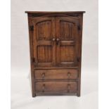 Oak reproduction linen cabinet enclosed by linen fold panel doors over two drawers, 122cm high x