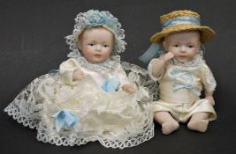 Pair of German small biscuit porcelain dolls with articulated head and limbs, dressed in matching