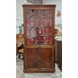 Late Georgian mahogany standing corner cupboard in two sections, the upper section enclosed by