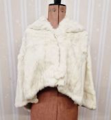 A vintage ermine cape, hooded, the back slightly longer than the front, with circular fur button