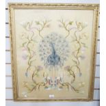 Early 20th century silk needlework picture of a peacock, standing between flowering branches, on