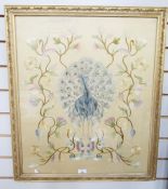 Early 20th century silk needlework picture of a peacock, standing between flowering branches, on