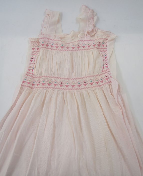 Two vintage night dresses with smocked detail to the neckline and bodice, one pink, one blue, a