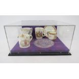 Collection of Royal Commemorative ceramics and glass within a perspex display case, including a