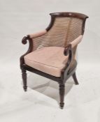 Early 19th century mahogany-framed bergere library chair with scroll arms and on leaf carved
