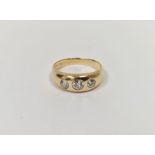 Gold and three-stone diamond ring set graduated stones in rubover setting, 6g gross (the diamonds