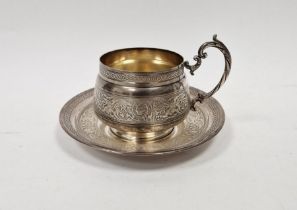 20th century French white metal cup and saucer, embossed phoenix and scrolling motifs throughout,