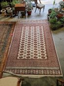 Eastern style cream ground carpet with four rows of 16 elephant foot guls enclosed by geometric