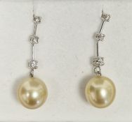 Pair of 14K white gold, diamond and pearl drop earrings, the beige pearl drops suspended from