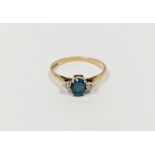 9ct gold, blue stone and diamond three-stone ring, the oval mid-blue-coloured stone flanked by two