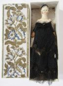 19th century carved and painted peg doll wearing a period black dress, 8cm long, housed in a small