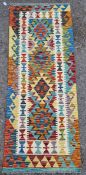 Chobi kilim runner, woven with geometric lozenges in red, blue, green, ochre and yellow within