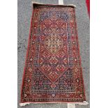 Middle Eastern red ground rug with hexagonal medallion to centre, reserved on a dense foliate ground