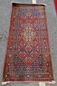 Middle Eastern red ground rug with hexagonal medallion to centre, reserved on a dense foliate ground