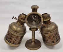 Two brass pierced cylindrical wall-mounted oil lamps, the first pierced with fretwork on baluster