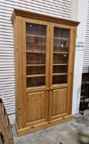 20th century pine display bookcase with two part-glazed cupboard doors opening to reveal
