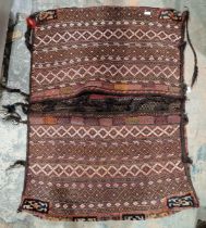 Woven carpet saddlebag, with interlocking lozenges and flowerhead bands on a dark red ground,