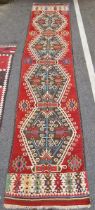 Caucasian kilim runner, woven with hexagonal foliate guls in cream, blue and red on a brown ground