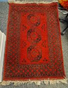 Middle Eastern red ground wool rug decorated with three octagonal guls, within a geometric pattern