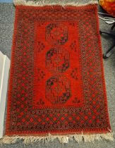 Middle Eastern red ground wool rug decorated with three octagonal guls, within a geometric pattern