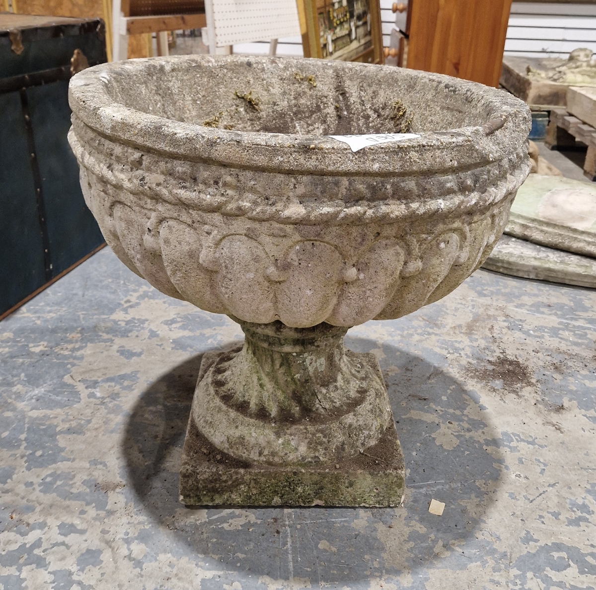 Reconstituted stone garden urn decorated with ropetwist and swag design, on wrythen column base,