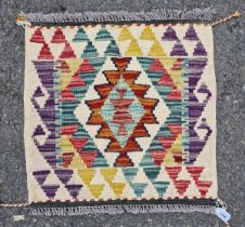 Chobi kilim, woven with a geometric medallion in red, blue and ochre reserved on a cream ground