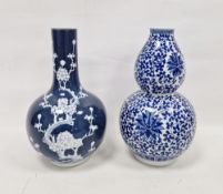 Two 20th century Chinese-style blue and white porcelain vases, first of double gourd form, decorated