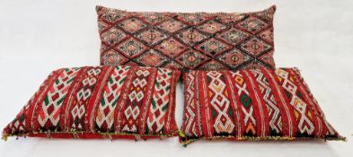 Two Moroccan camel bag-style cushions embellished with small discs and a bolster cushion covered
