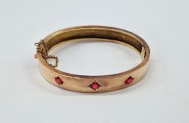 Gold coloured metal and ruby bangle set with three stones, 13.2g approx