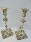 A pair of Edwardian silver table candlesticks, each with anthemion decorated shaped , square drip-