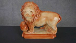 A Victorian Staffordshire figure of a male lion, one foot on a ball, raised on a rectangular base