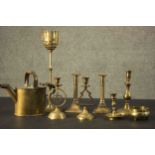 Three brass candle holders and a brass 19th century watering can along with four brass candle