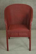 A red Lloyd Loom woven wicker tub chair, bearing brass Lloyd Lloom label.