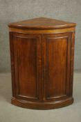 A 19th century oak bow fronted corner cabinet, with two doors opening to reveal a shelf on a