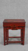 An early 20th century Chinese red lacquered nest of tables, rectangular with traditional designs