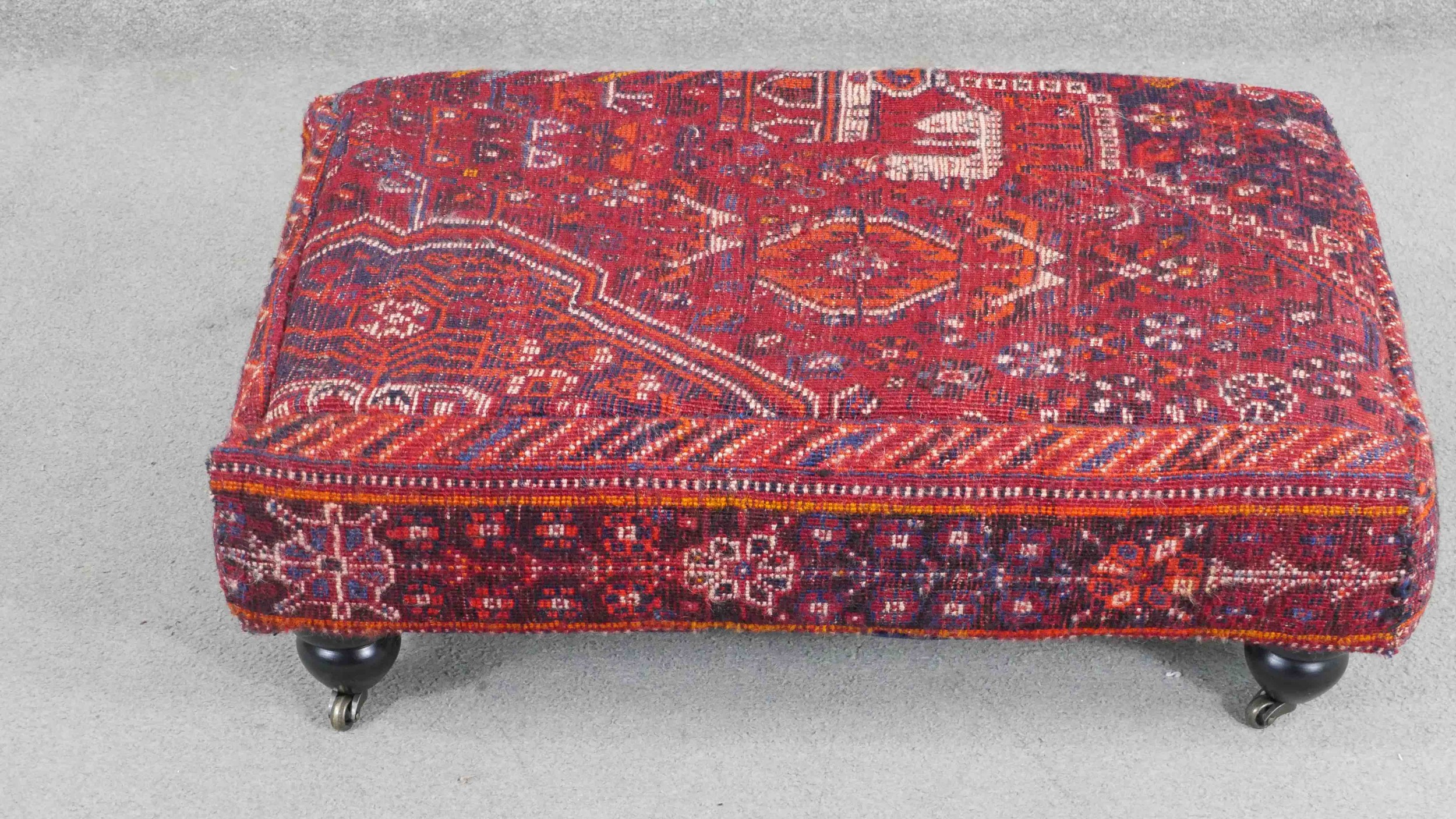 A contemporary rectangular footstool, upholstered in an antique kilim, on turned bulbous legs with
