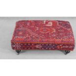 A contemporary rectangular footstool, upholstered in an antique kilim, on turned bulbous legs with