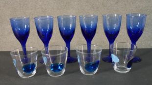 A set of six blue art glass wine glasses along with a set of four clear glasses with blue glass