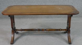 A Bevan Funnell Ltd 'Reprodux' mahogany coffee table, with a tooled leather top on lyre end supports