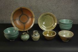 A collection of art pottery, including a set of seven pale blue glaze dessert bowls, a large stone