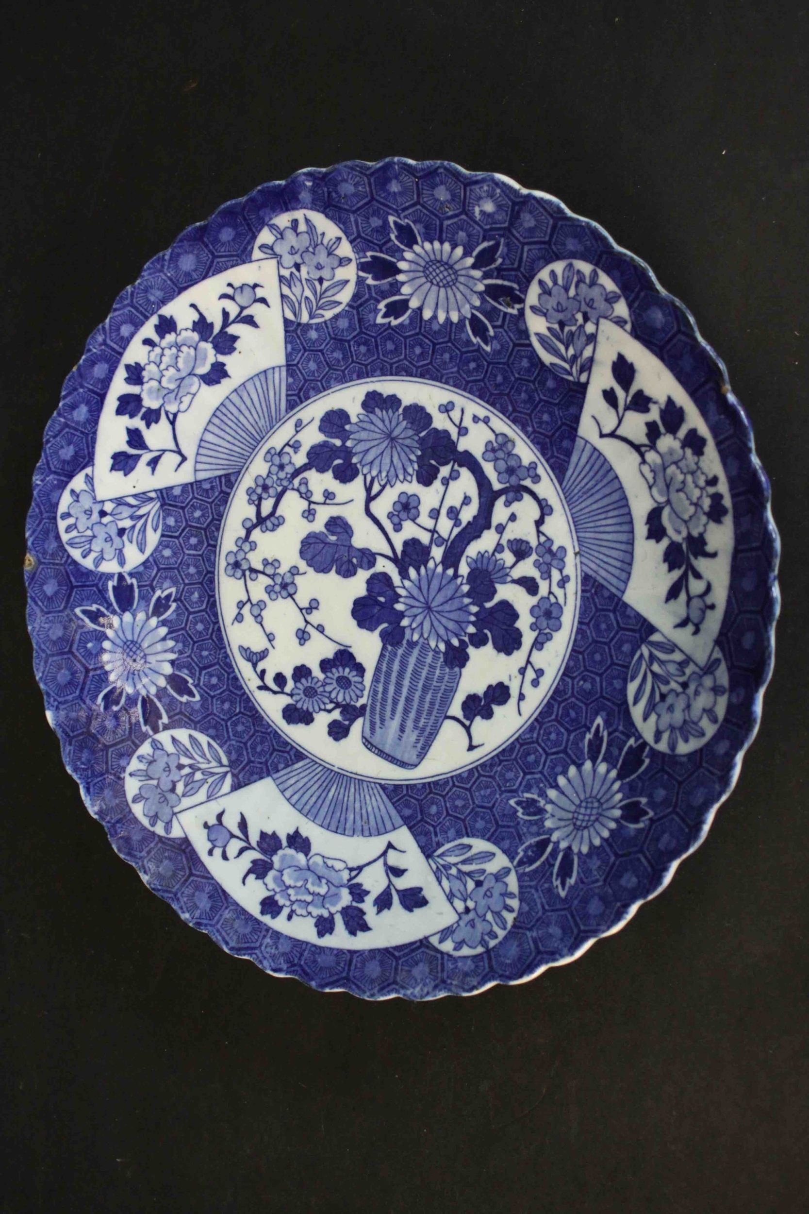 A large 19th century Japanese blue and white scalloped edge ceramic charger with transfer design