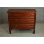 A late Victorian style hardwood chest of three long drawers with knob handles and fluted bands, on