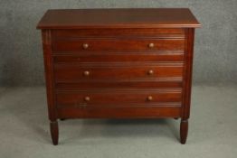 A late Victorian style hardwood chest of three long drawers with knob handles and fluted bands, on