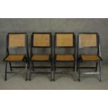 A set of four 20th century ebonised folding chairs, with caned backs and seats.